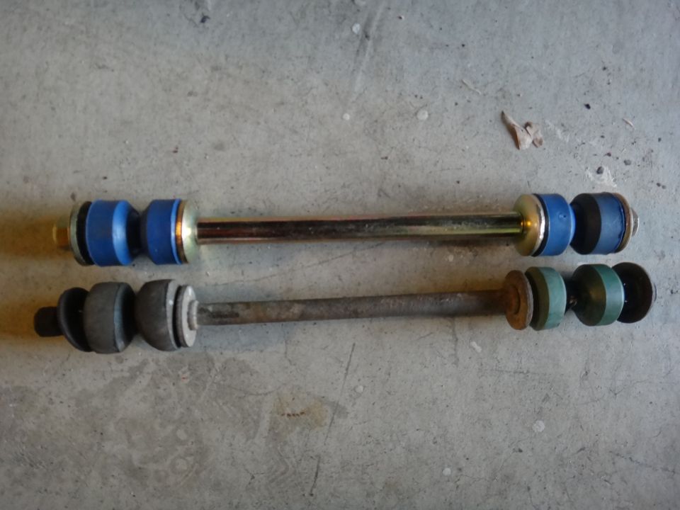 Two sway bar links, one new with blue bushings, one old with green and gray bushings
