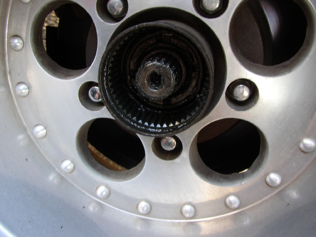 Close-up of a greasy locking hub in center of silver alloy wheel