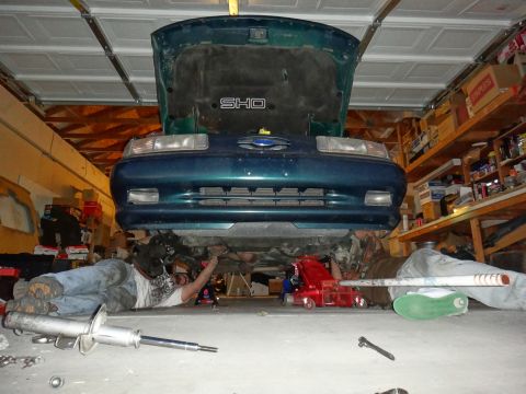 1993 Ford Taurus - A green 1993 Ford Taurus SHO is shown from the front with its hood open while someone works underneath it in a garage.