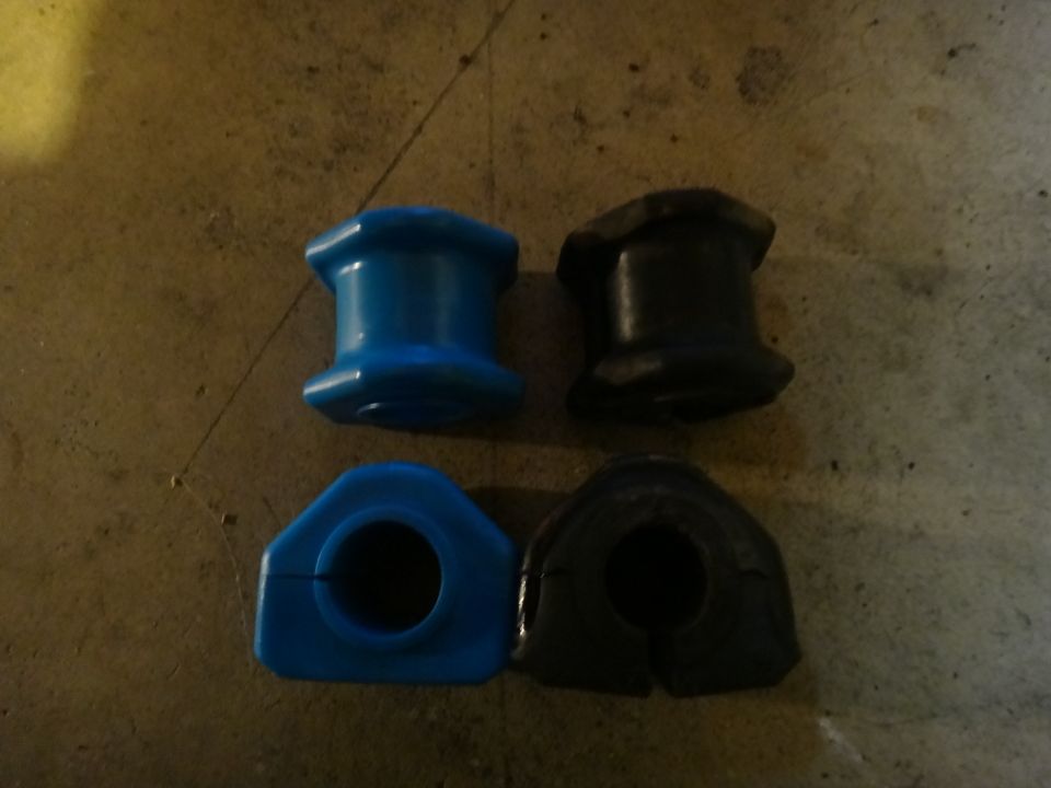 two blue and two black suspension bushings on a concrete surface