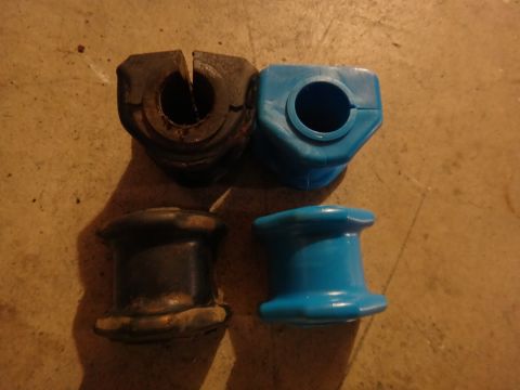 1993 Ford Taurus - Comparison of old and new suspension bushings, one set black and worn, the other blue and new.