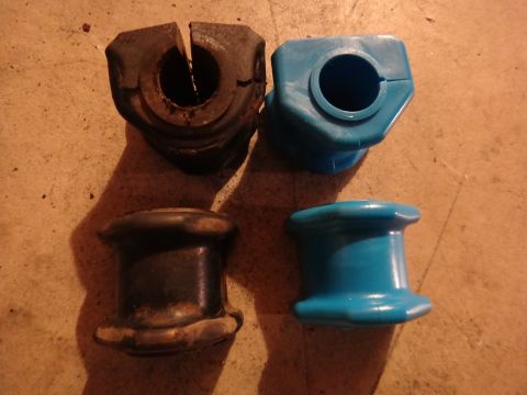 1993 Ford Taurus - Two old, worn suspension bushings are shown next to two new, bright blue replacements.