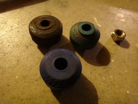 1993 Ford Taurus - Set of suspension bushings and a nut on a concrete floor.