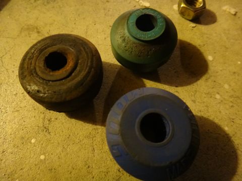 1993 Ford Taurus - Close-up of three different suspension bushings and a nut, likely automotive parts.