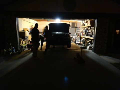 1993 Ford Taurus - People working on a car inside a dimly lit garage at night.