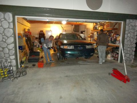 1993 Ford Taurus - A green 1993 Ford Taurus is shown in a garage as two people work on it.