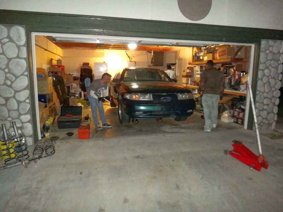 Green 1993 Ford Taurus front view in garage with people working on it