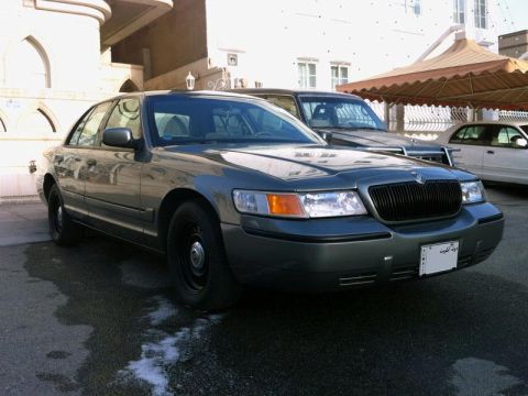 2001 Mercury Grand Marquis - A dark gray sedan is parked in front of a building with another vehicle behind it.