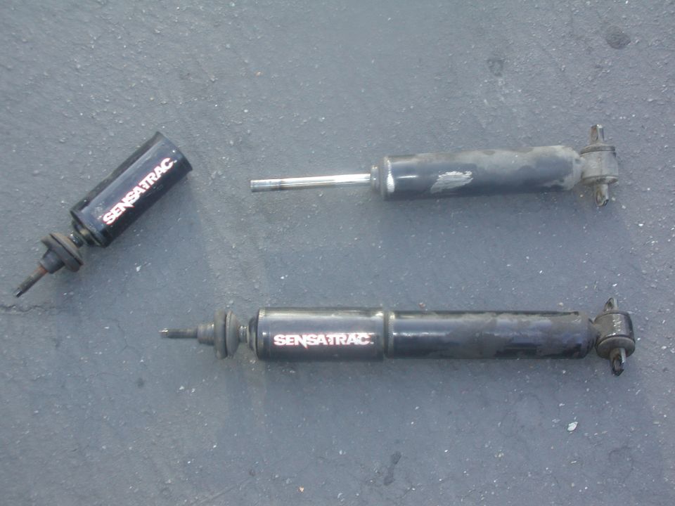 Three Sensa-Trac shock absorbers on gray pavement