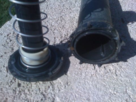 1968 Ford Mustang - Close-up view of a shock absorber spring and its housing, resting on a concrete surface.