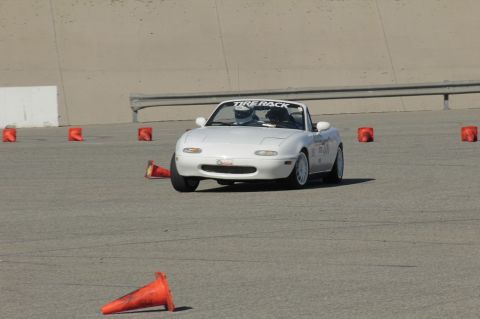 1991 Mazda Miata - White 1991 Mazda Miata navigates a course marked by orange cones, with a "TIRE RACK" banner visible.