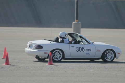 1991 Mazda Miata - A white convertible sports car navigates a course marked by orange cones.