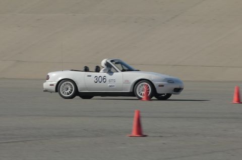 1991 Mazda Miata - A white 1991 Mazda Miata is shown on a race track, navigating around orange cones.