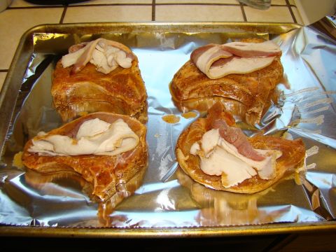 1989 Ford Bronco - Four pork chops prepared for baking, each topped with slices of bacon and turkey, arranged on a foil-lined baking sheet.