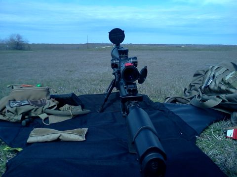 1996 Ford Bronco - A sniper rifle is set up on a tripod in an open field, with tactical gear nearby.