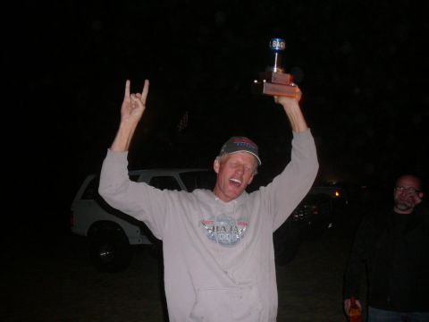 1988 Ford Bronco - A man celebrates with a trophy in front of a white 1988 Ford Bronco at night.