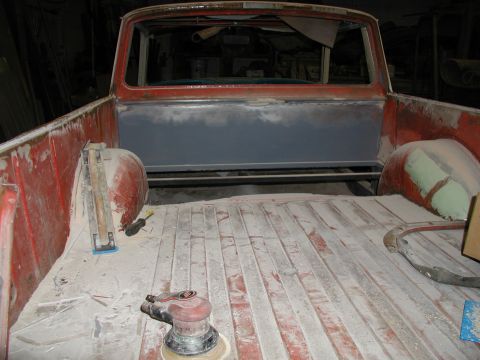 1960 Ford Ranchero - The bed of a pickup truck is shown with bodywork in progress, including sanding tools and primer on the rear panel.