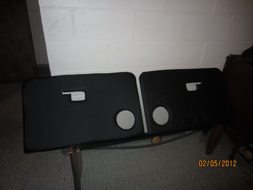 Two black door panels with circular cutouts and rectangular handle openings, resting on a metal frame