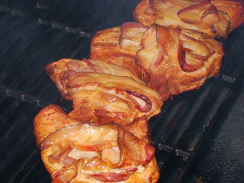1989 Ford Bronco - Food items wrapped in bacon are cooking on a dark metal grill.