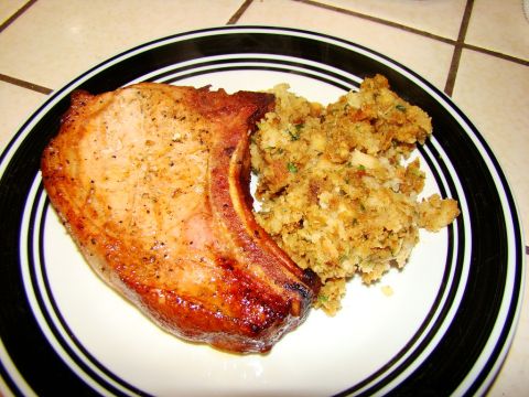 1989 Ford Bronco - A cooked pork chop is served with a side of stuffing on a plate with a black and white rim.