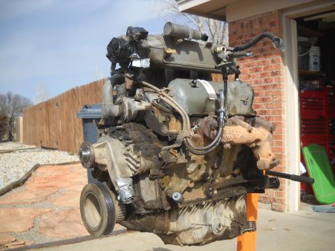 1992 Ford Explorer - A disassembled engine sits on a stand in front of a brick garage and wooden fence.