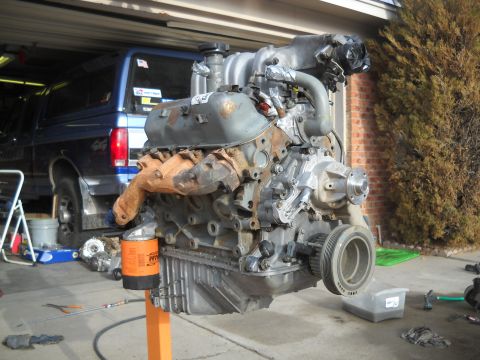 1992 Ford Explorer - An engine is mounted on a stand, with a blue pickup truck visible behind it.