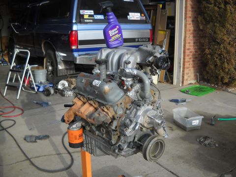 1992 Ford Explorer - V8 engine on an engine stand, with a blue Ford truck visible in the garage.