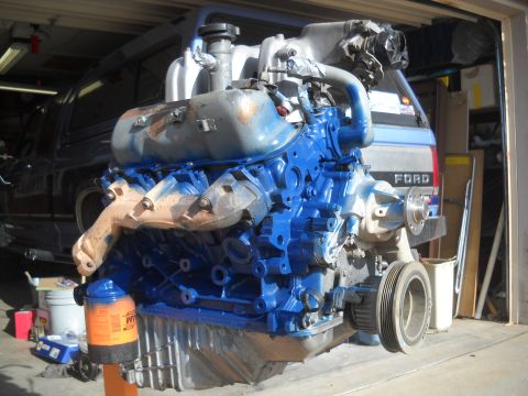 1992 Ford Explorer - V8 engine on a stand, with a Ford truck visible in the garage behind it.