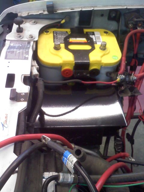1996 Ford Bronco - Close-up of a vehicle's engine bay a yellow Optima battery and red electrical cables.