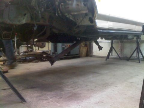 1996 Ford Bronco - The underside of a vehicle is visible, supported by jack stands, with suspension parts exposed.