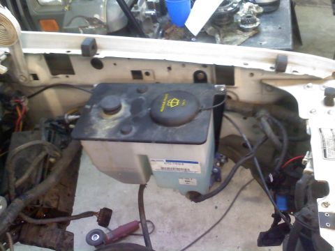 1996 Ford Bronco - Close-up view of a vehicle's engine bay, focusing on the windshield washer fluid reservoir and surrounding components.