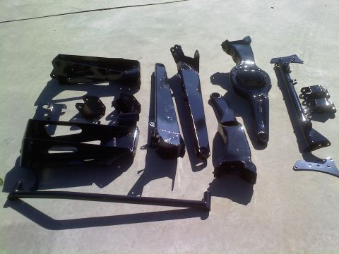 1996 Ford Bronco - Various suspension parts, likely for a custom build, are arranged on a paved surface.