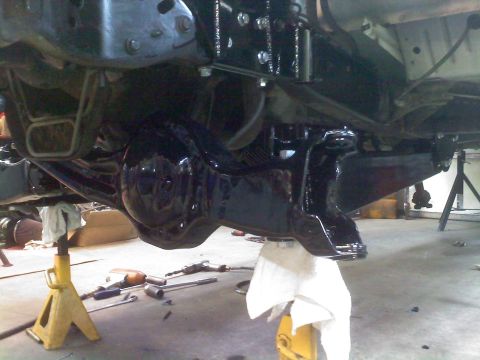 1996 Ford Bronco - The vehicle's undercarriage is visible, with suspension parts painted black and the vehicle supported by jack stands.