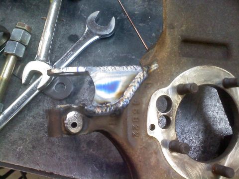 1996 Ford Bronco - Close-up of a suspension component undergoing welding, showing heat treatment colors and a stamped part number.