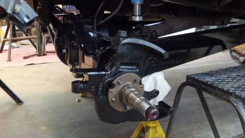 1996 Ford Bronco - Front suspension knuckle and hub assembly undergoing work, supported by jack stands.