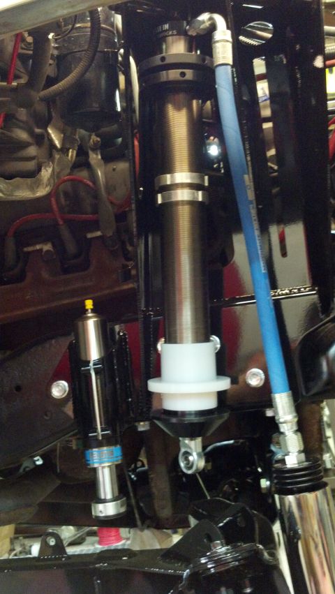1996 Ford Bronco - Close-up of custom suspension components, including a shock absorber and reservoir, with a blue hydraulic hose.