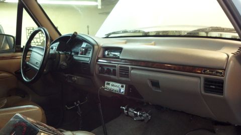 1996 Ford Bronco - The dashboard of a truck features wood trim and a CB radio, with the hood open.