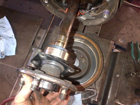 1965 Ford Mustang - Close-up of a car's wheel hub, brake drum, and axle assembly during maintenance.