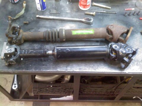 1996 Ford Bronco - Comparison of two driveshafts, one appears to be a replacement for the other. Tools are scattered around.