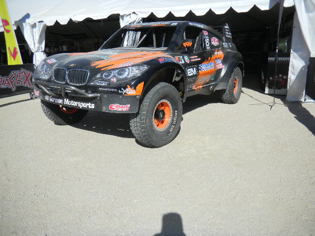 Black off-road race truck with orange graphics, front view
