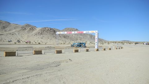 1997 Ford Ranger - A desert scene with off-road vehicles gathered near a start/finish line arch.