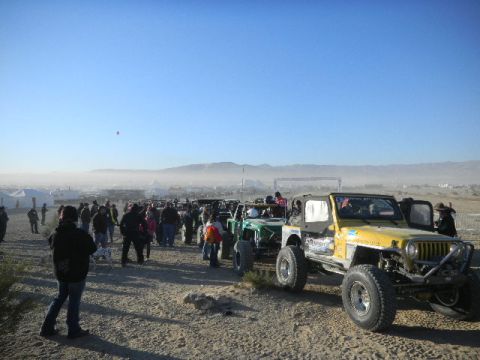 1997 Ford Ranger - A line of off-road vehicles and people gathered in a desert landscape under a clear blue sky.