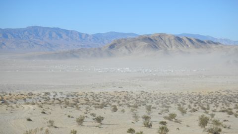 1997 Ford Ranger - A wide desert scene with mountains in the background and a town in the distance, a Supermotors logo.