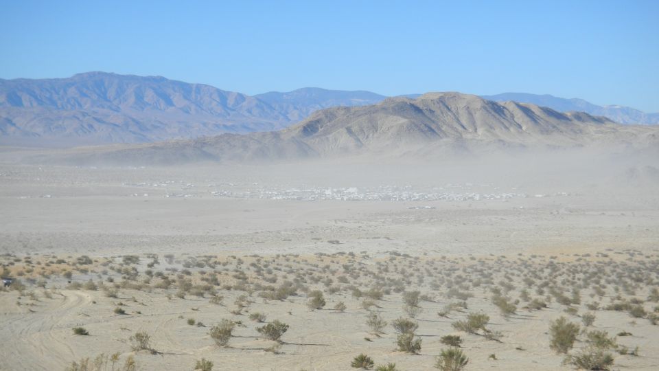 Desert landscape with mountains and a distant town, supermotors.net logo