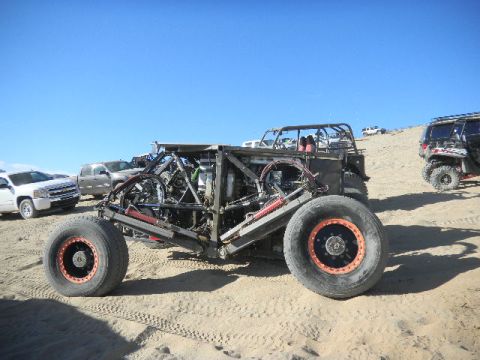 1997 Ford Ranger - Custom buggy with large tires and exposed mechanicals sits on sandy terrain under a clear blue sky.