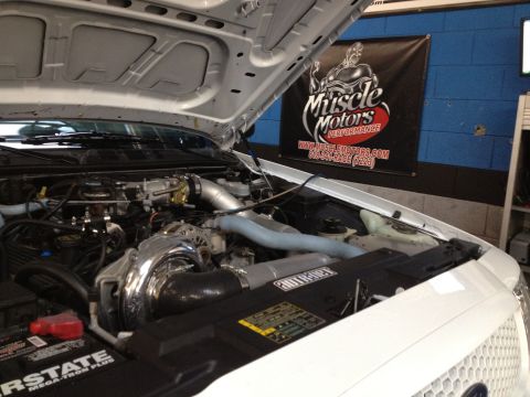 2004 Ford Crown Victoria - The engine bay of a 2004 Ford Crown Victoria features a prominent supercharger and custom piping.
