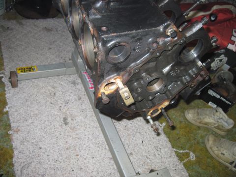 2005 Ford Excursion - An engine block is shown on a stand, with visible rust and oil on the surrounding floor.
