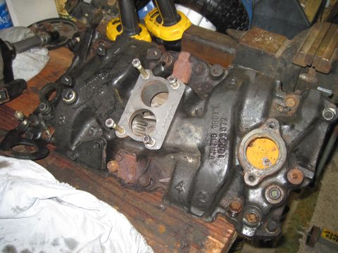 2005 Ford Excursion - A black engine intake manifold with visible casting numbers and a metal flange is shown on a workbench.