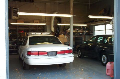 1998 Ford Crown Victoria - KC's garage with a '95 P71 being reconditioned. The car next to it is a nice Medium Wedgewood Blue '95 P71. (large pic)