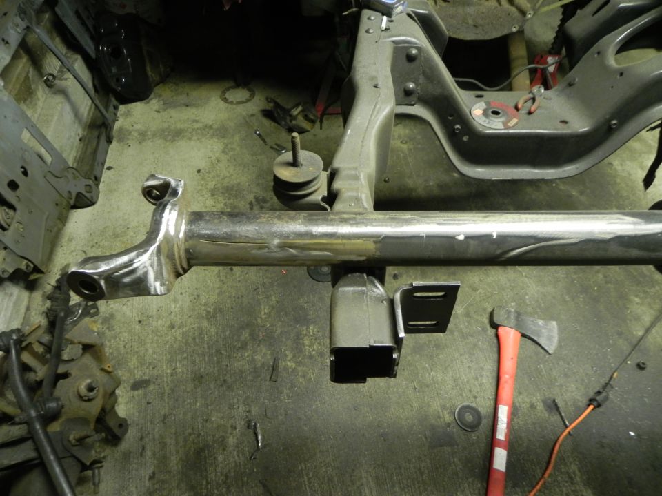 Chrome-plated suspension component with welded brackets and an axe on a workshop floor